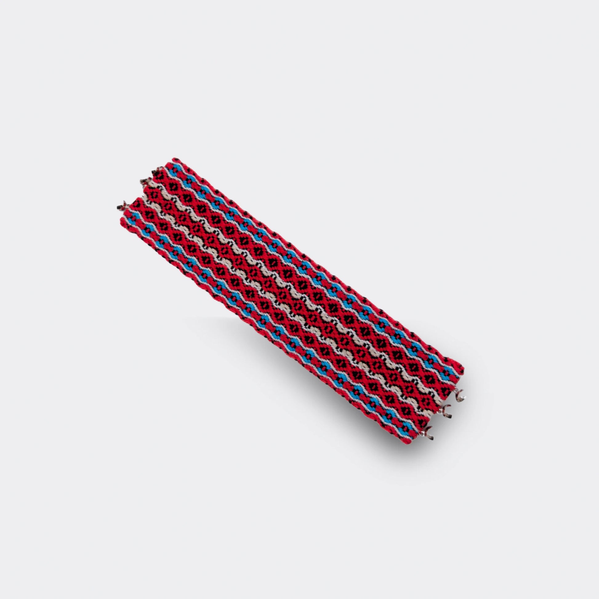 Bracelet tissé rouge et bleu, tissage manuel dense et structuré, reflets du travail du fil artisanal, vue dépliée de la manchette
