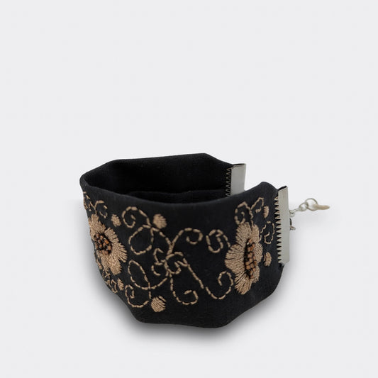 Détail du motif floral central d’un bracelet noir et champagne, brodé à la main sur brocart. Artisanat balkanique réinterprété