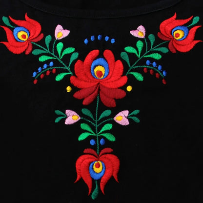 Zoom sur la broderie florale Matyó sur ce T shirt à manches courtes. Le rouge des grandes fleurs est éclatant et la forme évocatrice de traditions encore ancrées dans la Hongrie d'aujourd'hui.