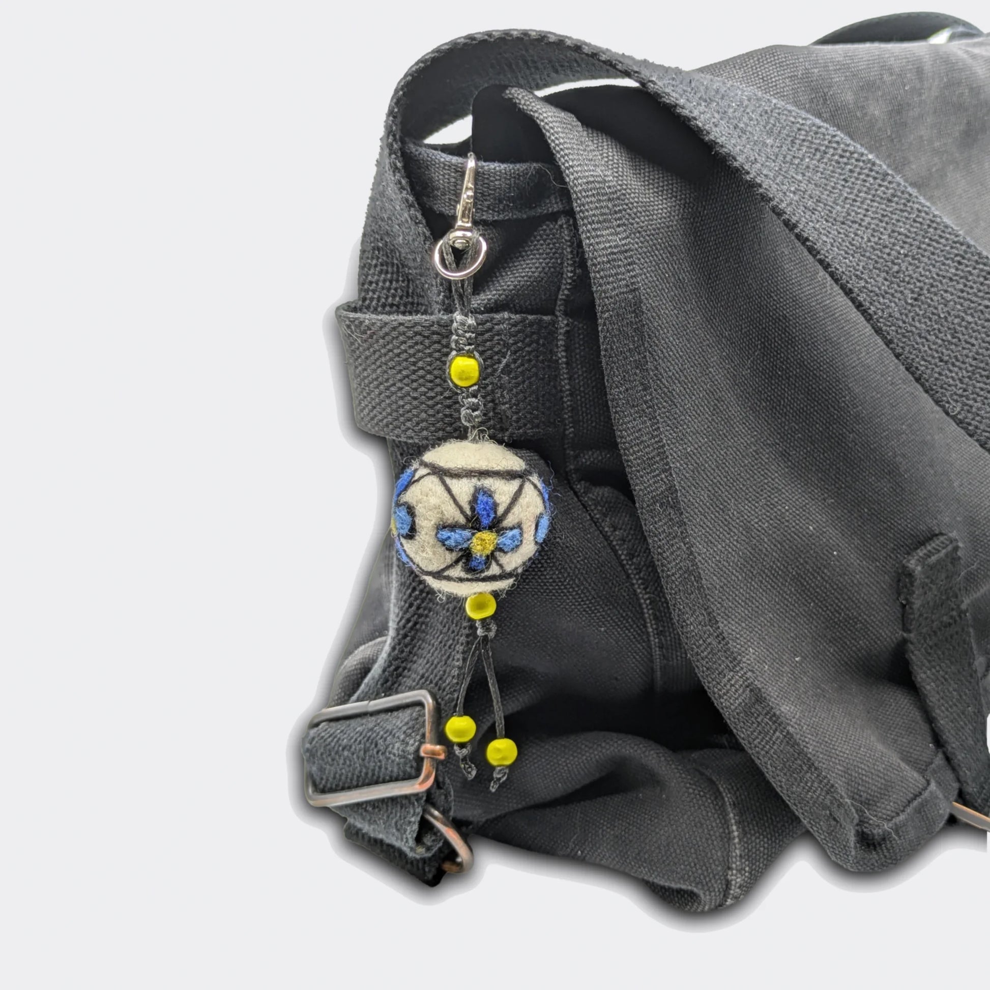 Breloque Milena accrochée sur sac avec boule en feutre décorée de fleurs bleues. Entièrement fait main.