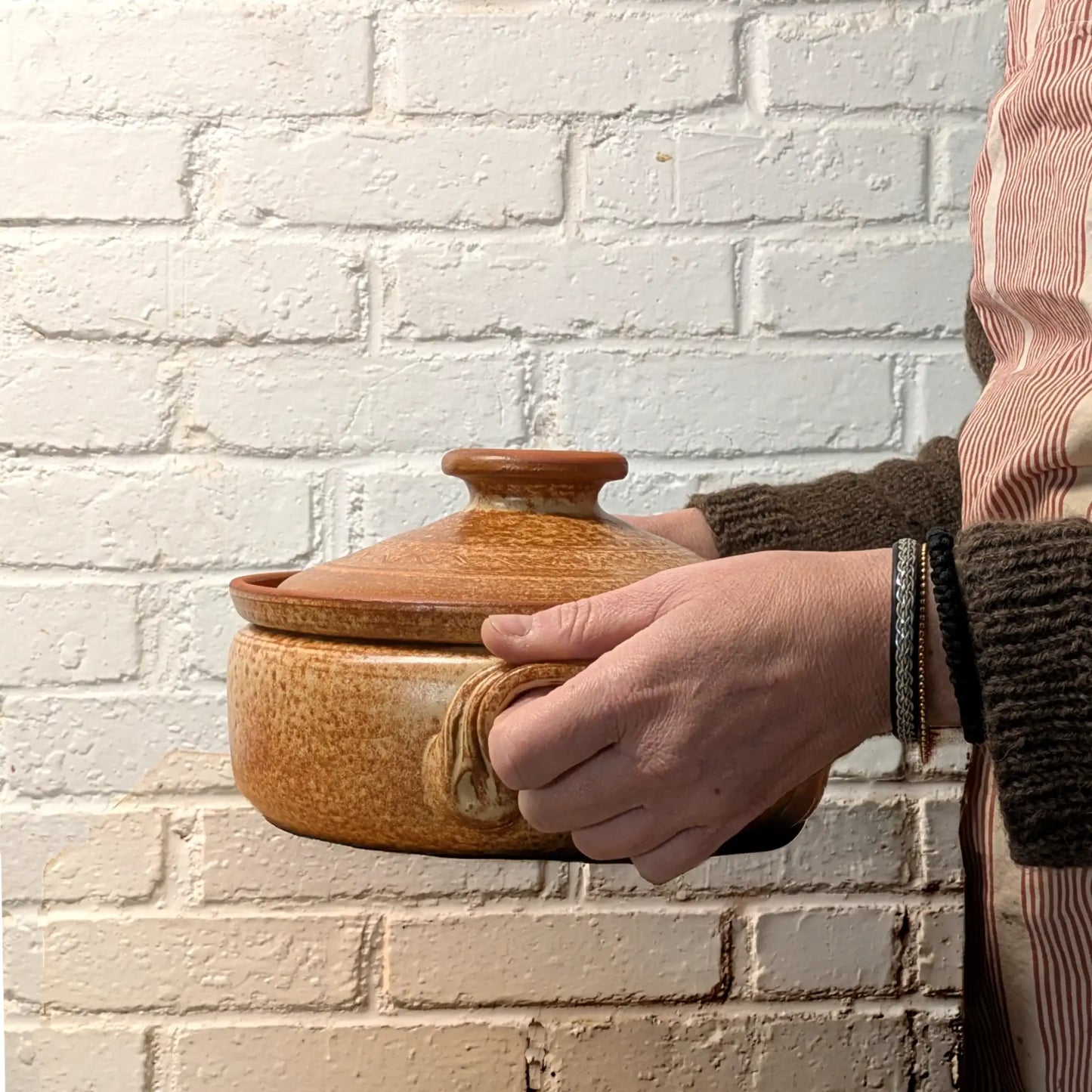 Mini cocotte en terre cuite 2 litres tenue dans les mains, poterie artisanale de Corund adaptée aux petites préparations.