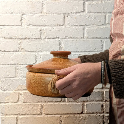 Mini cocotte en terre cuite 2 litres tenue dans les mains, poterie artisanale de Corund adaptée aux petites préparations.