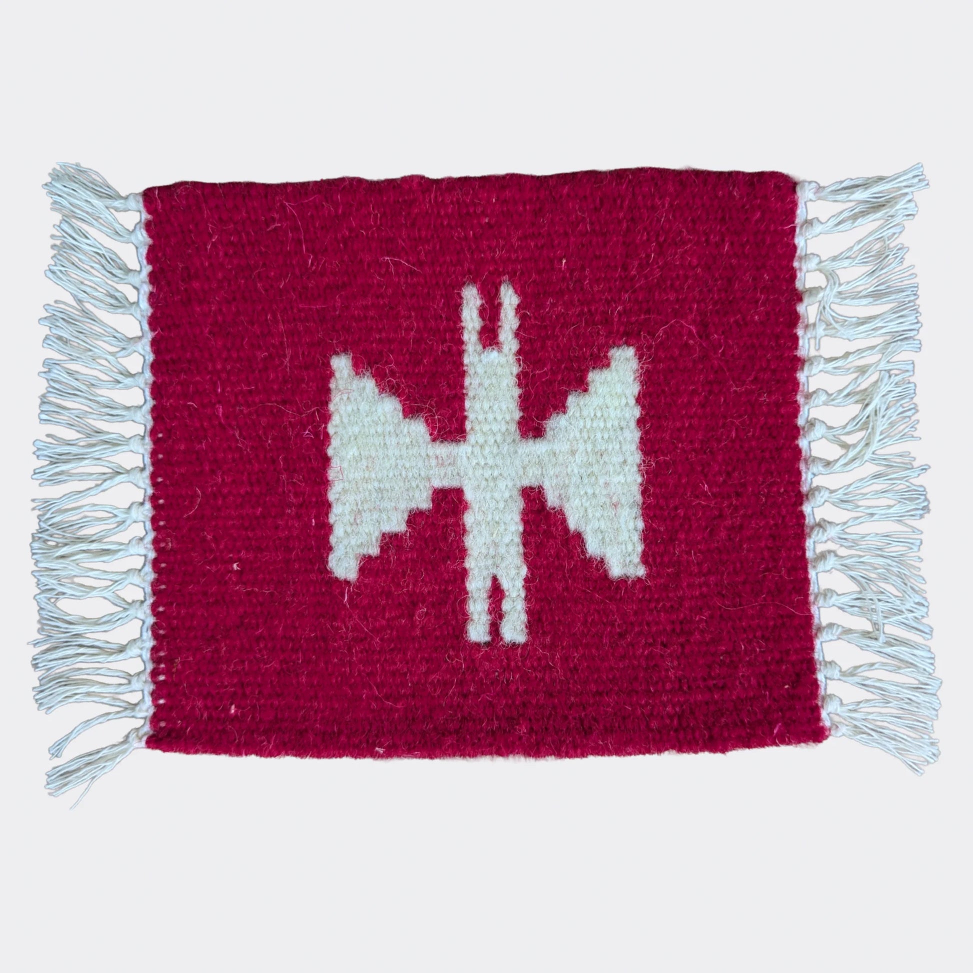 Mini tapis en laine rouge avec un motif géométrique blanc cassé. Texture tissée main, un mini tapis artisanal au contraste marqué.