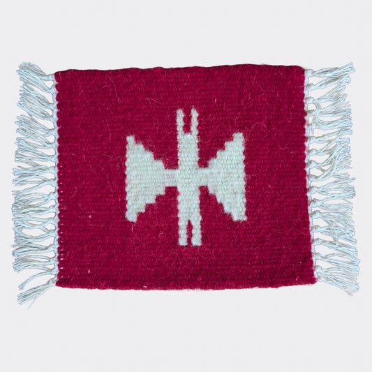 Mini tapis en laine rouge avec un motif géométrique blanc cassé. Texture tissée main, un mini tapis artisanal au contraste marqué.