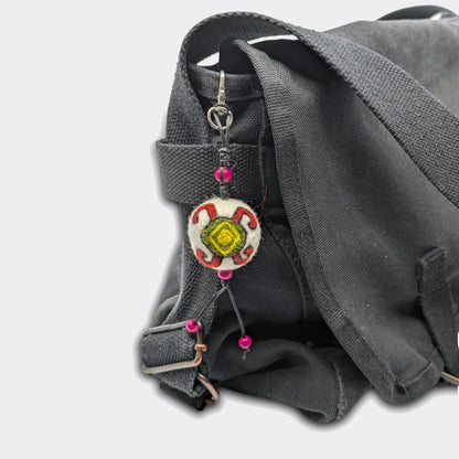 Vue de la breloque Mirna en feutre avec motif tortue rouge, jaune et verte traditionnelle