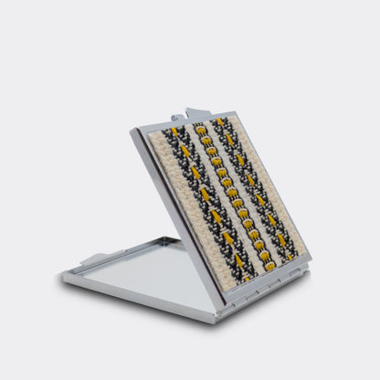 Miroir compact orné d’un motif textile jaune. Les frises tissées apportent une note d’Europe centrale. Idéal pour accompagner les gestes beauté.