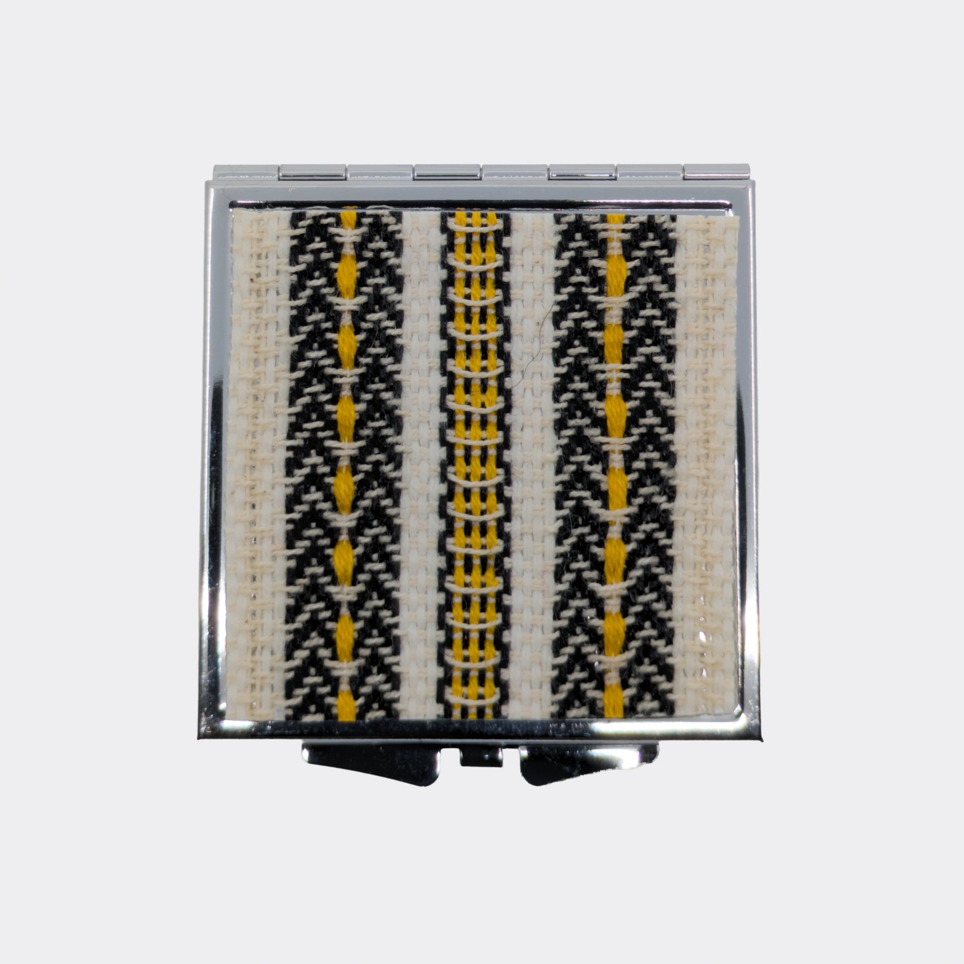 Miroir de poche ouvert avec frises jaunes tissées. Les couleurs évoquent les textiles d’Europe centrale. Parfait pour de petites retouches.