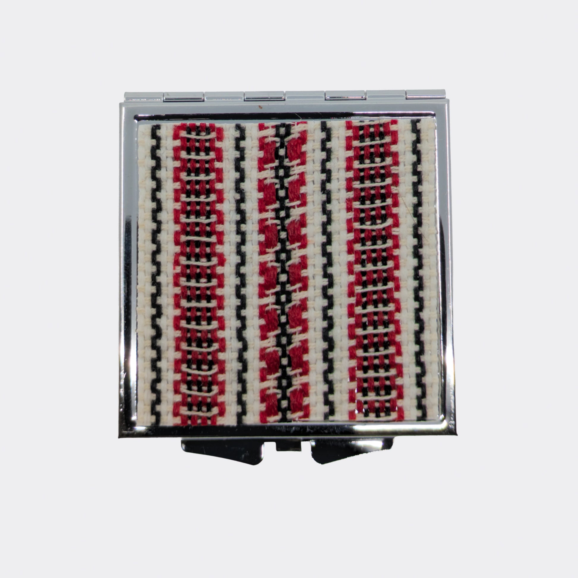 Miroir compact orné d’un motif textile rouge et noir. Le décor tissé apporte une note douce venue des Carpates. Idéal pour glisser dans un sac.