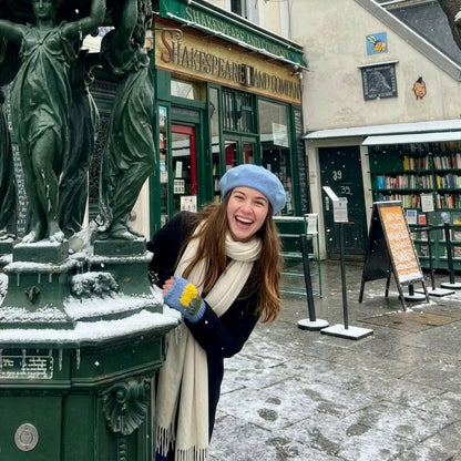 Mitaines artisanales bleues à décor floral, portées en extérieur devant une librairie, avec bonnet assorti et ambiance hivernale