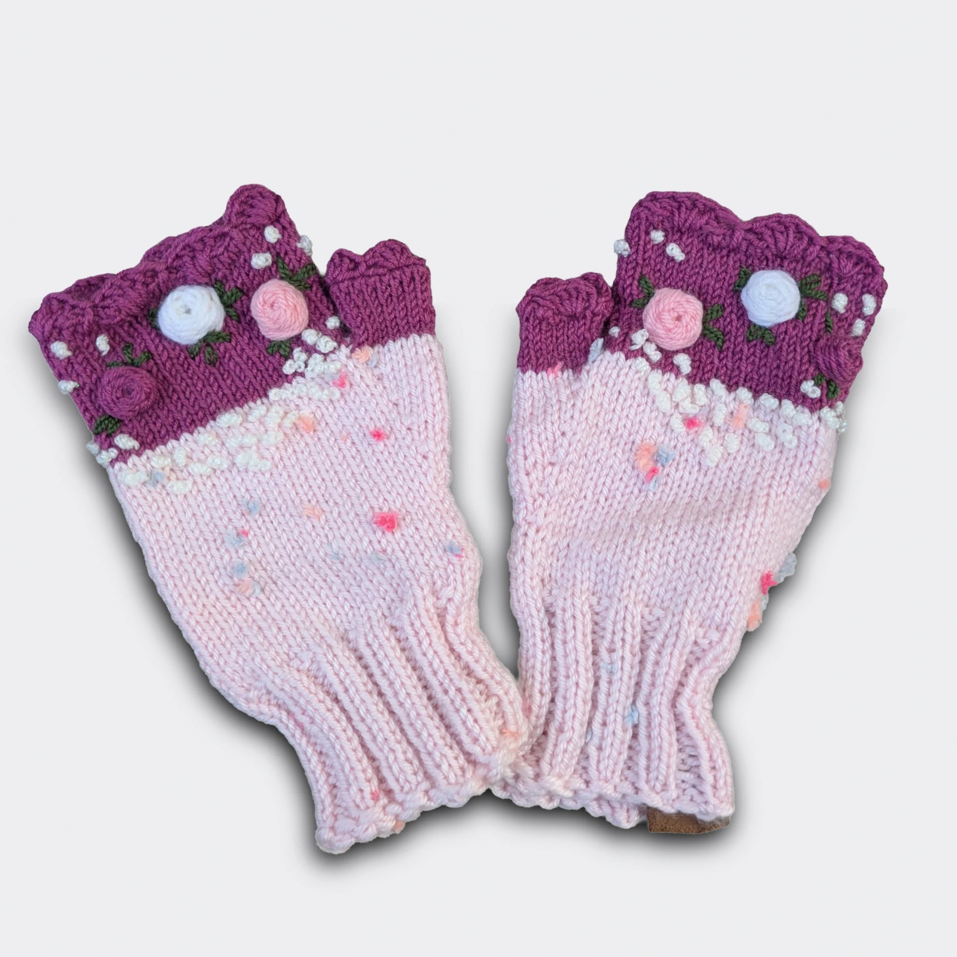 Mitaines artisanales bicolores roses, fleurs crochetées et bord festonné.