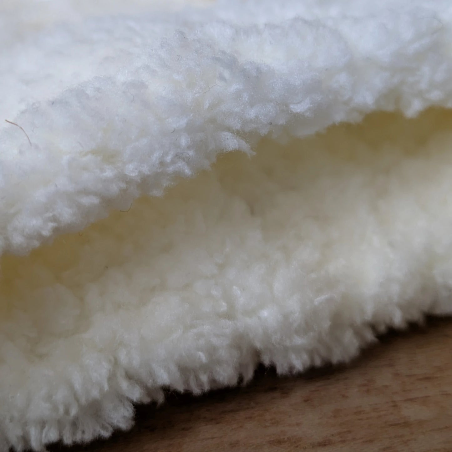 Détail de la finition pelucheuse au poignet sur des mitaines blanches faites main.