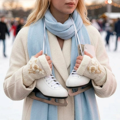 Mitaines brodées blanches avec fleur en relief et ourlets pelucheux, portées en extérieur dans une scène parisienne d’hiver.
