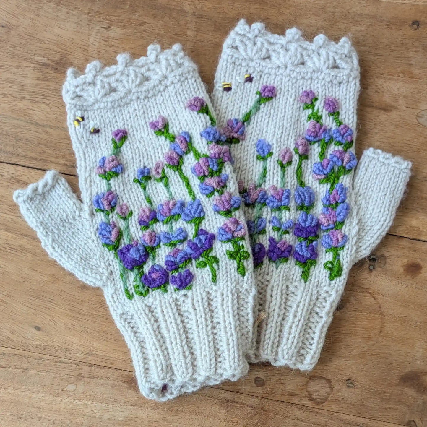 Mitaines gris clair tricotées main, avec fleurs mauves et violettes brodées et deux abeilles décoratives.