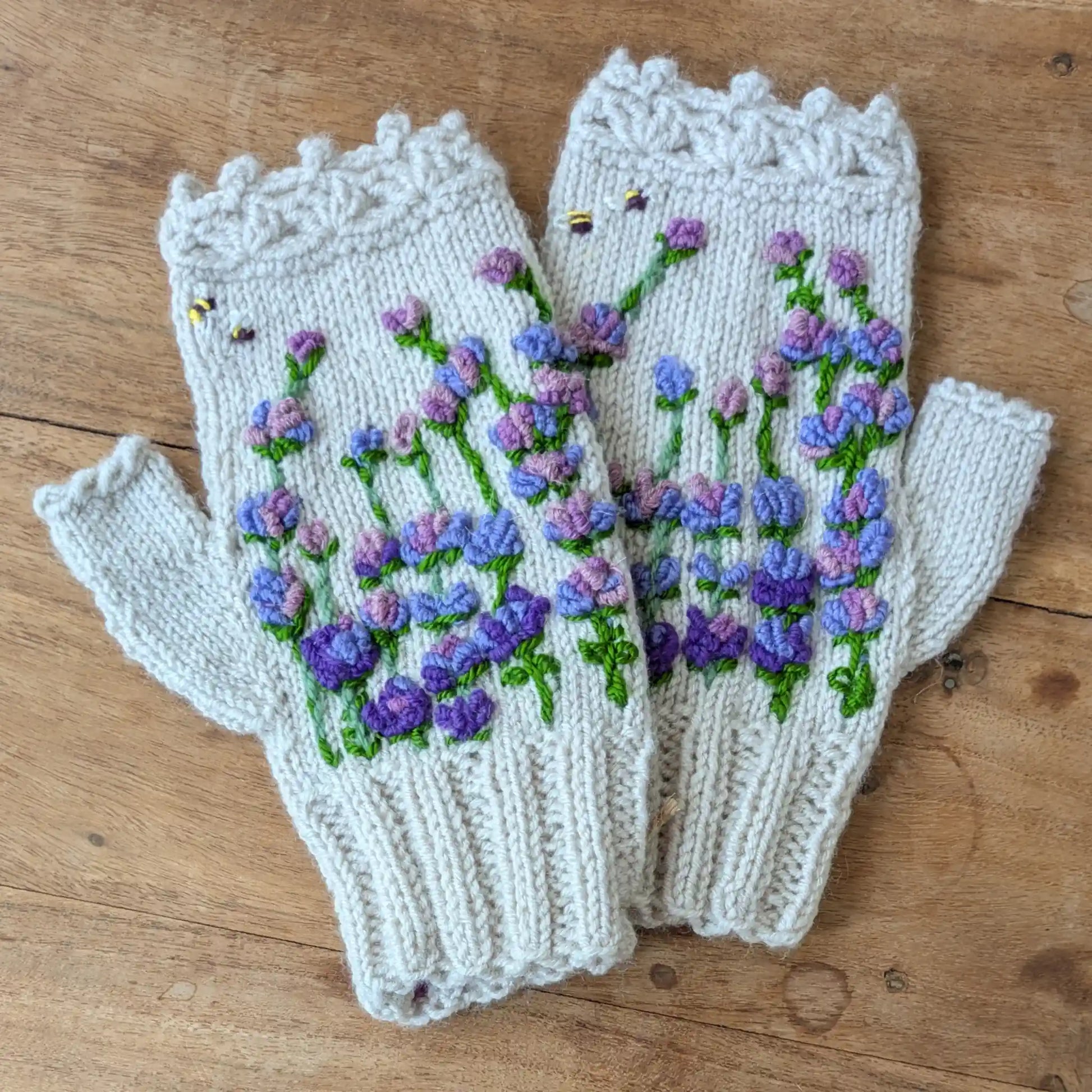 Mitaines gris clair tricotées main, avec fleurs mauves et violettes brodées et deux abeilles décoratives.