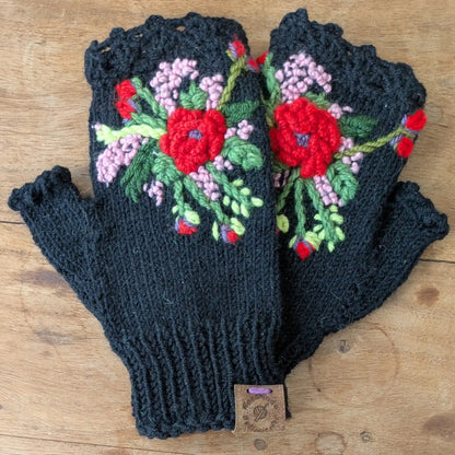 Mitaines noires tricotées main avec décor floral rouge, rose pâle et vert sur le dessus.