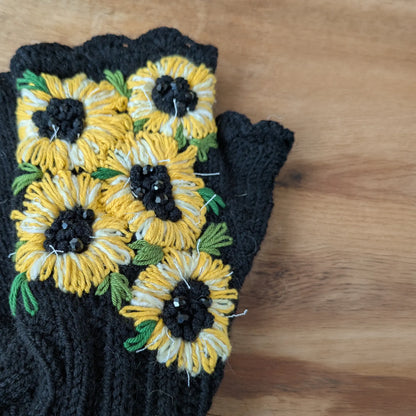 Mitaines noires tricotées main avec grands tournesols jaunes et cœurs noirs en perles.