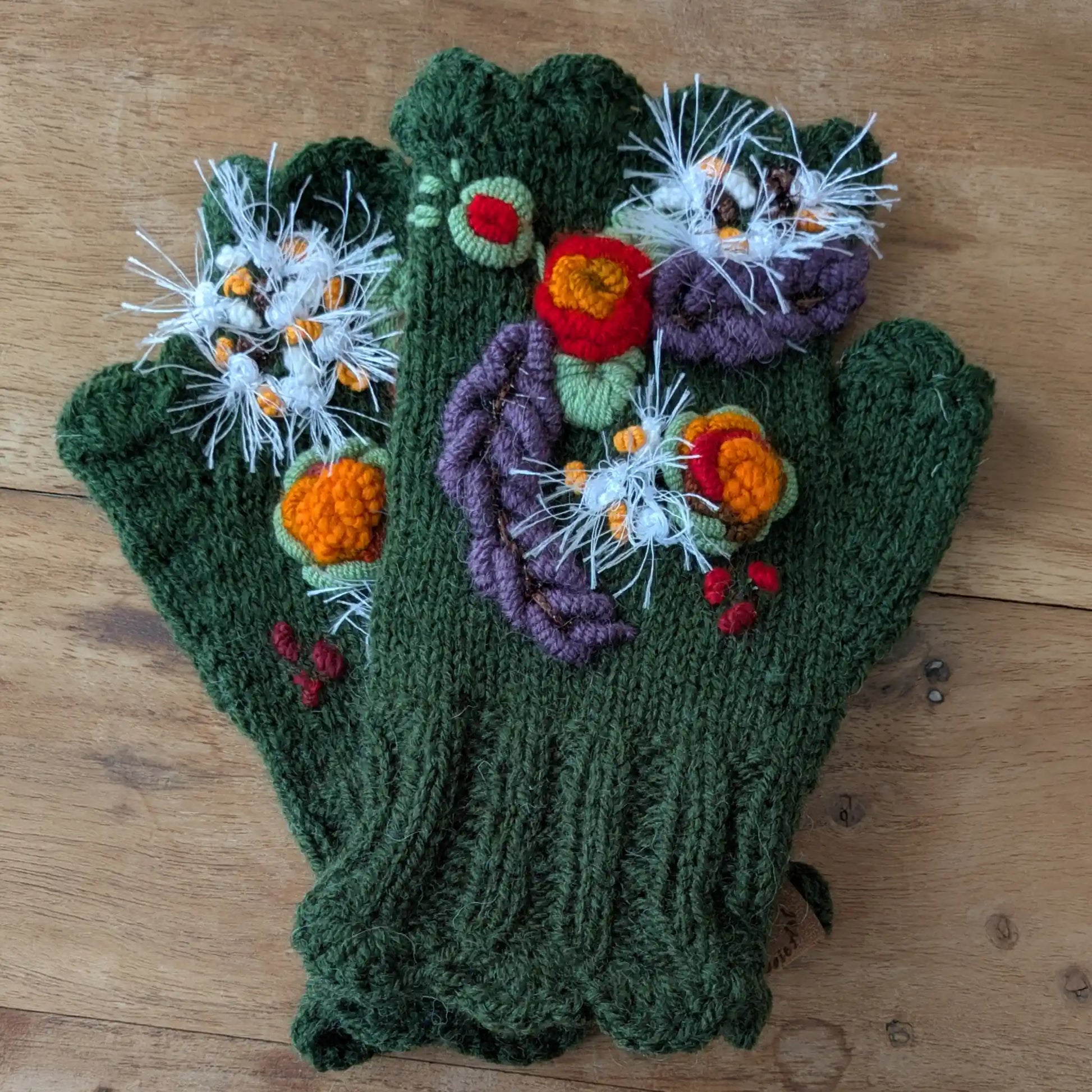 Mitaines vert olive tricotées main, avec fleurs colorées appliquées et broderies végétales.