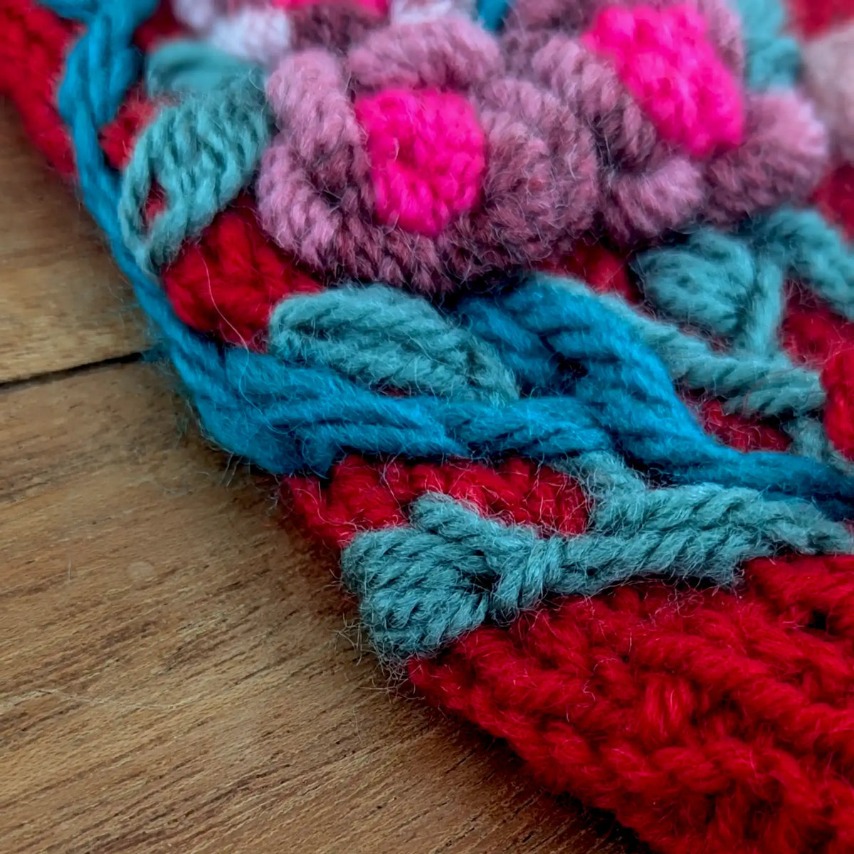 Gros plan sur une mitaine faite main de fabrication artisanale On y voit des fleurs brodées sur la mitaine de couleur rouge.