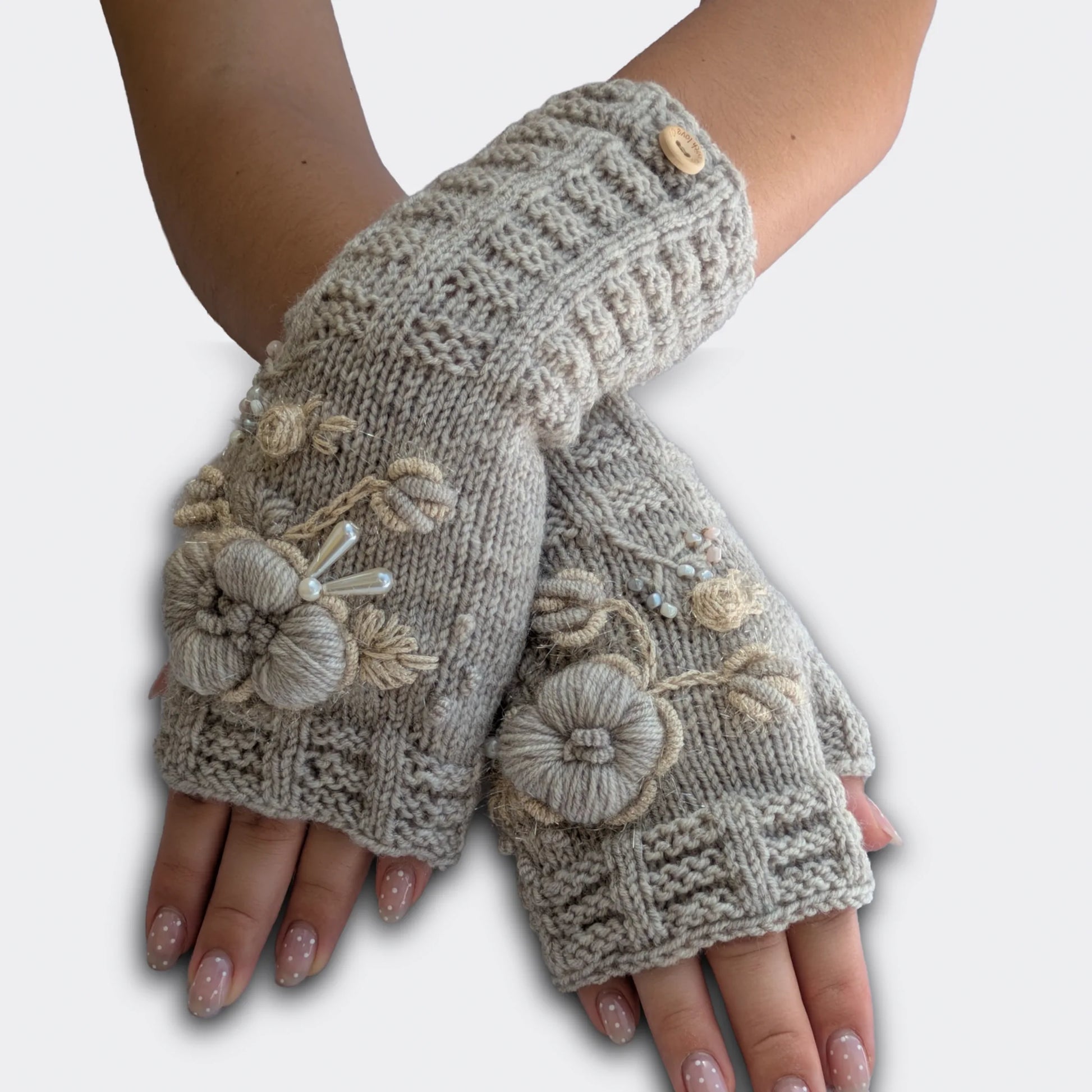 Mitaines gris clair tricotées main portées mains croisées, avec fleurs beige-écru brodées et petits boutons décoratifs