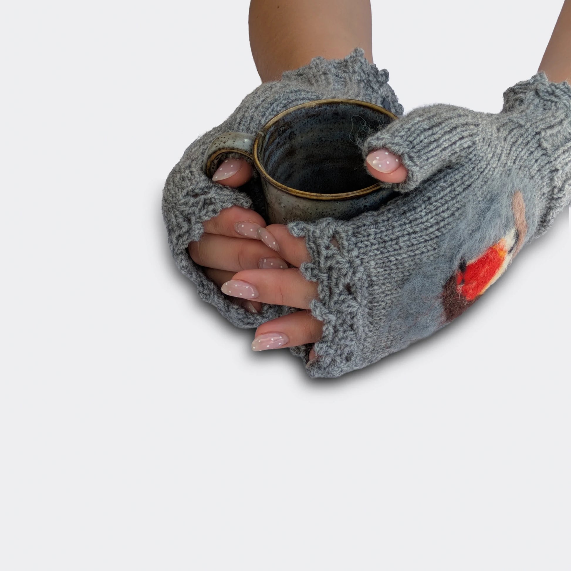 Mitaines grises tenant une tasse, avec motif rouge-gorge en relief et finition festonnée.