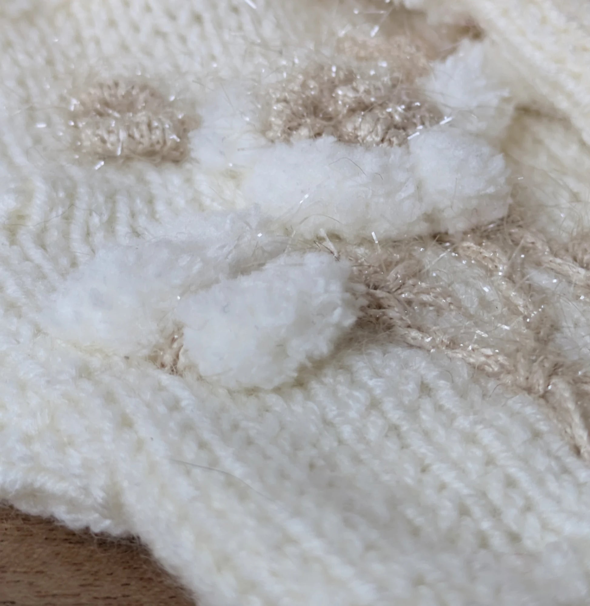 Gros plan sur la fleur blanche en relief et les petites boules appliquées sur les mitaines.