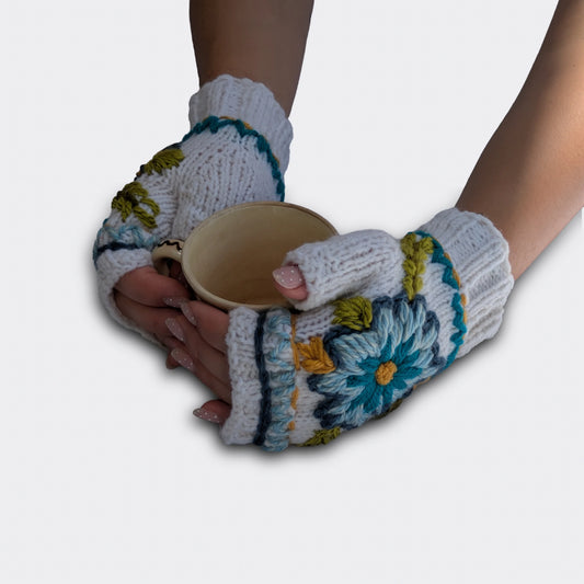 Mitaines blanc cassé tenant une tasse, avec décor floral bleu et turquoise et bord festonné au crochet.