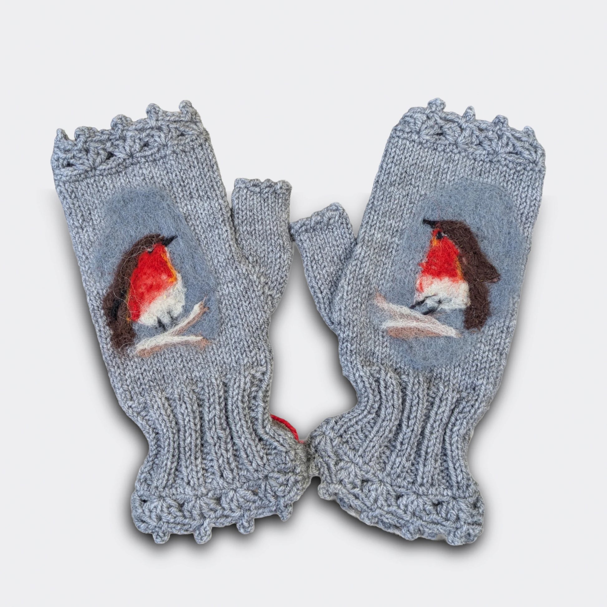 Détail d'une paire de mitaines artisanales grises avec rouge-gorge en feutre appliqué sur la maille. Finition festonnée.