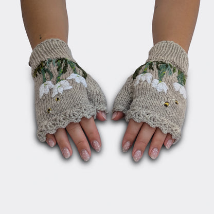 Mitaines tricotées main gris perle portées à plat, avec crocus blancs crochetés puis brodés et feuillage vert.