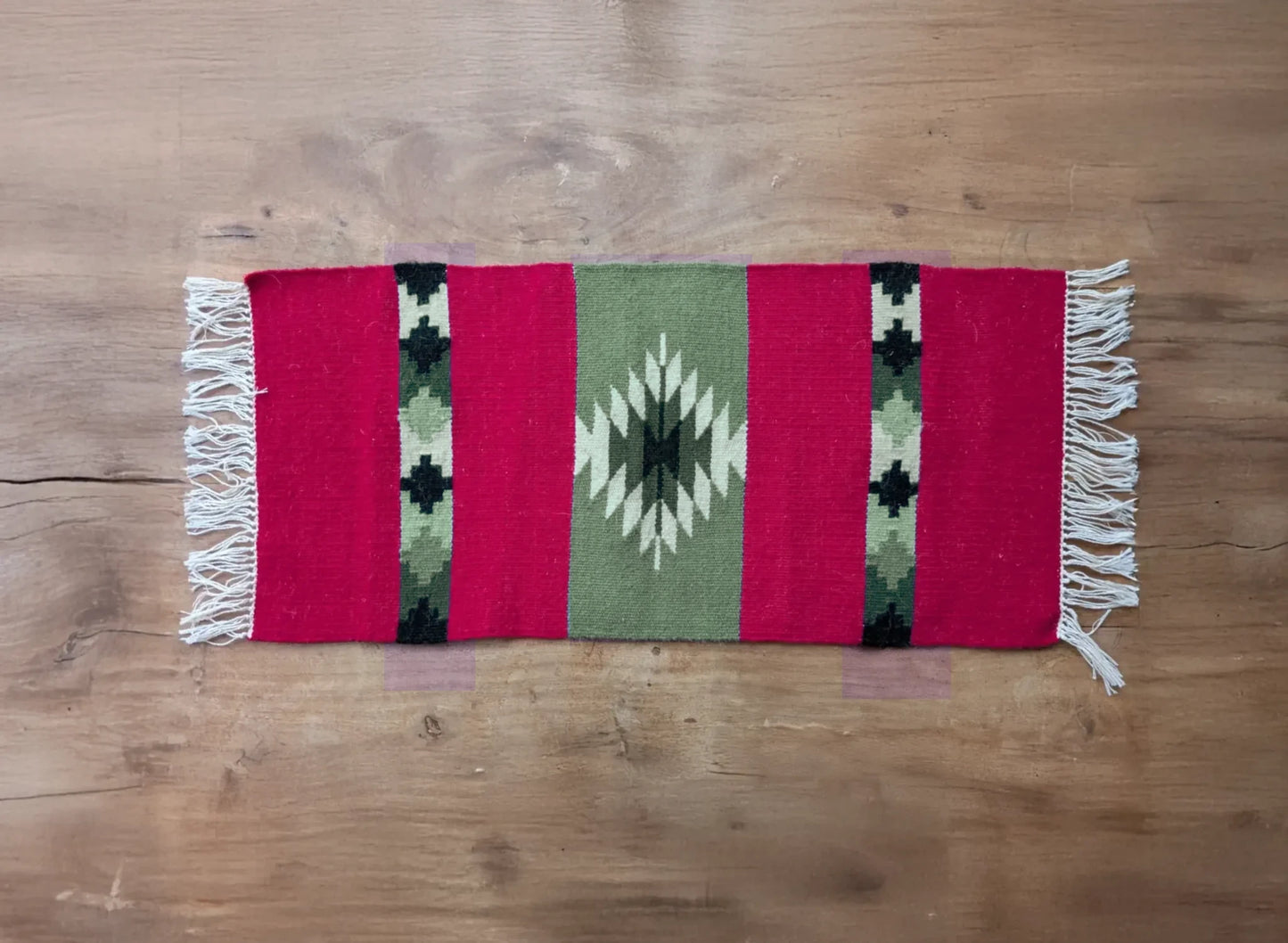 Vue d’ensemble d’un tapis artisanal rouge et vert du Montenegro. Les bandes verticales et le motif central offrent une esthétique traditionnelle.