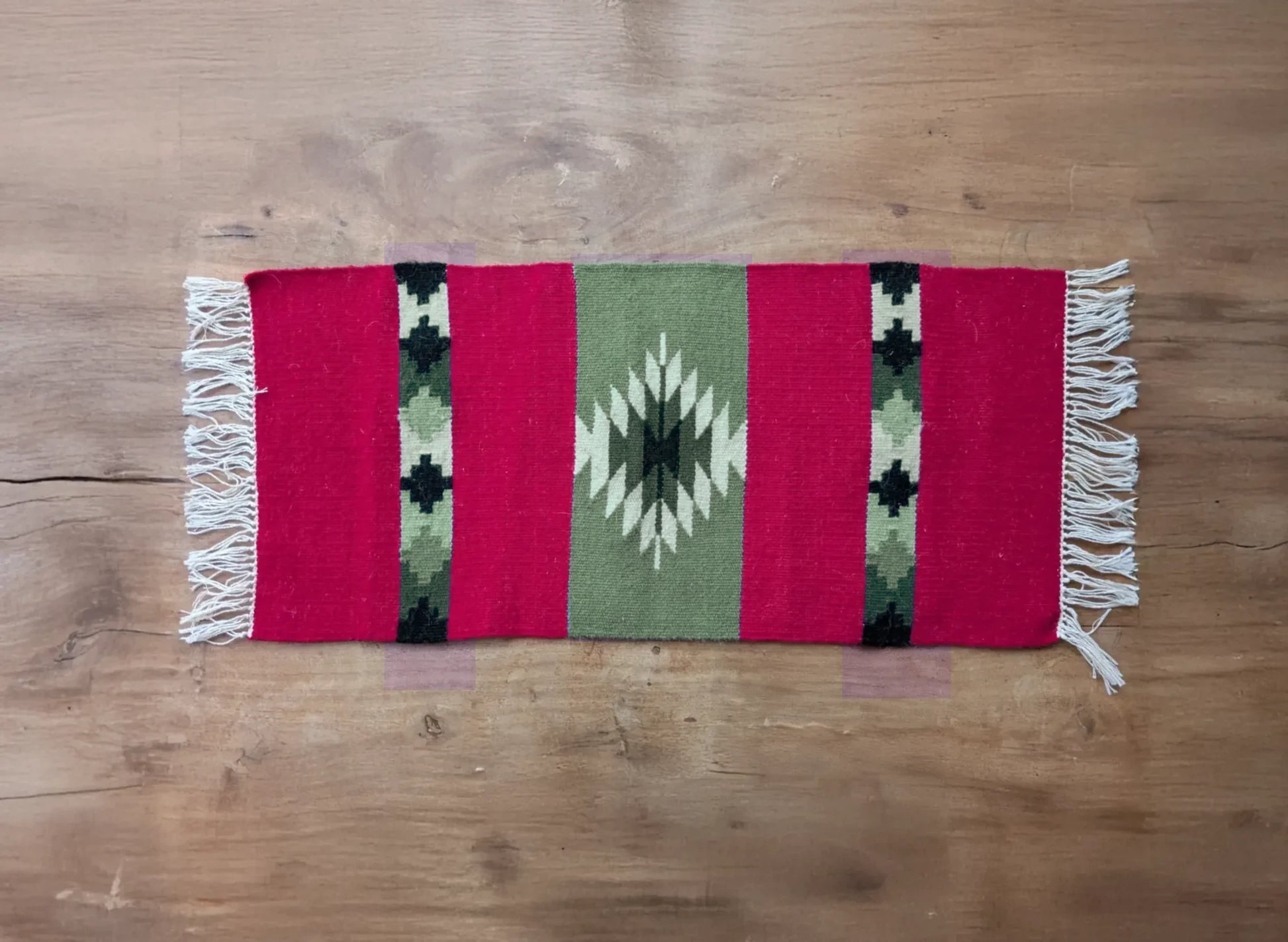 Vue d’ensemble d’un tapis artisanal rouge et vert du Montenegro. Les bandes verticales et le motif central offrent une esthétique traditionnelle.