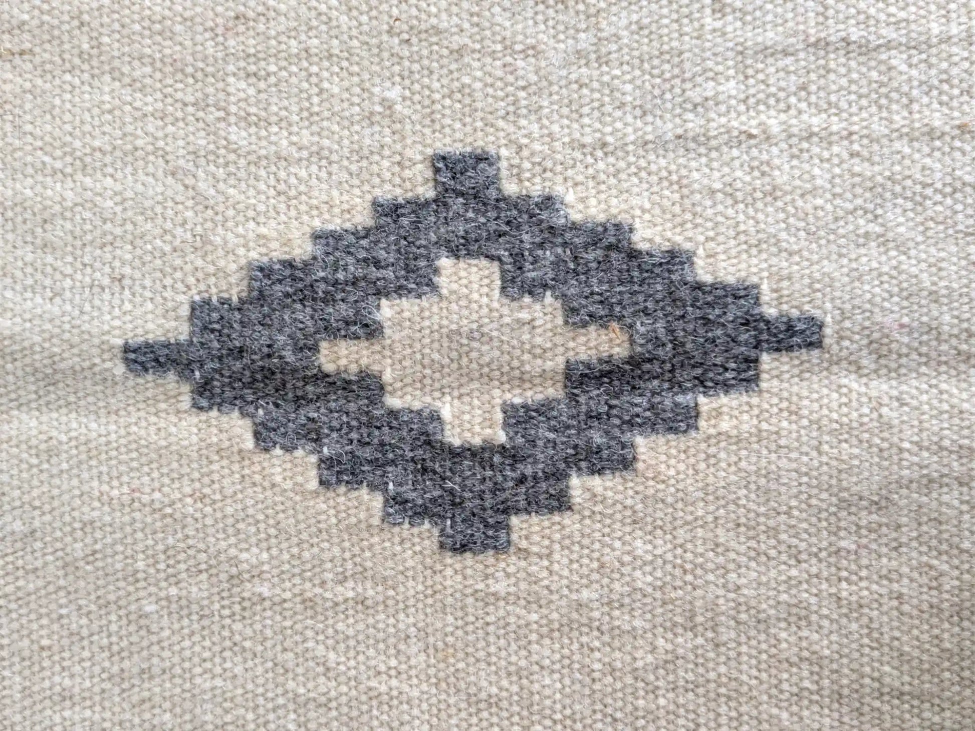 Motif kilim gris sur fond crème, détail du losange central tissé à la main