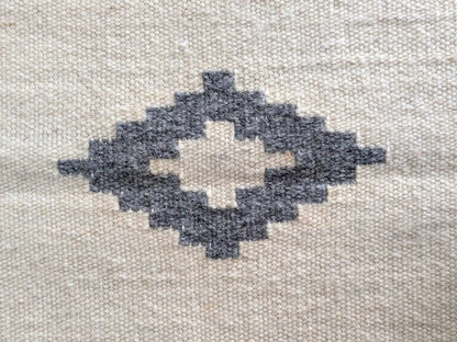 Motif kilim gris sur fond crème, détail du losange central tissé à la main