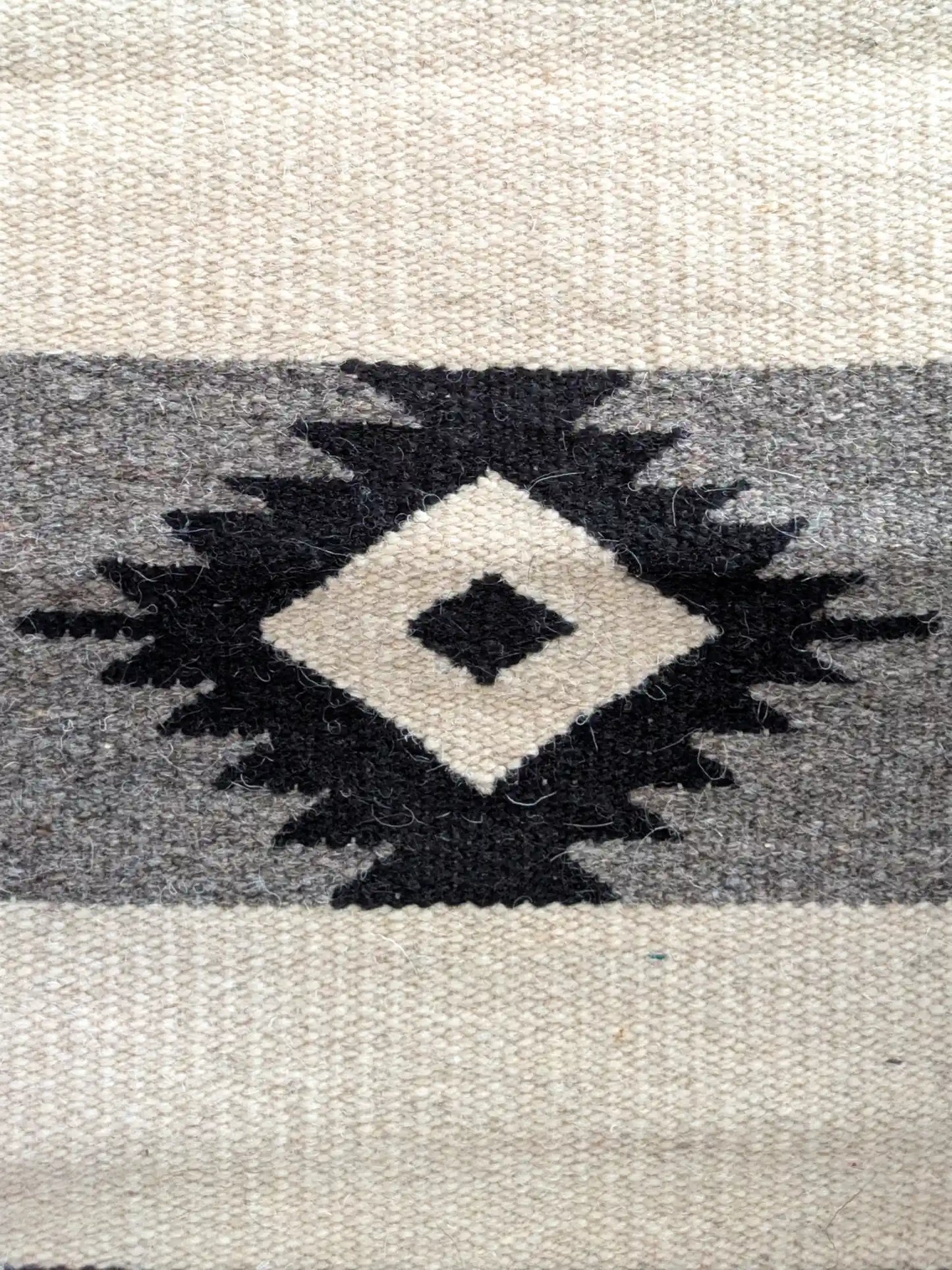 Motif kilim en losange noir sur laine écrue et grise, détail du tissage à plat