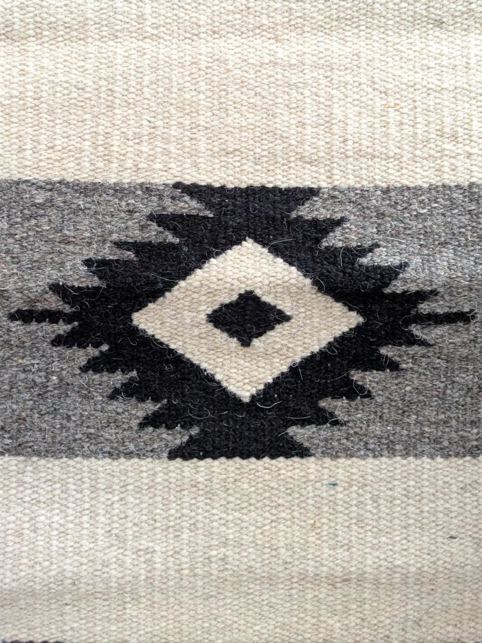 Motif kilim en losange noir sur laine écrue et grise, détail du tissage à plat
