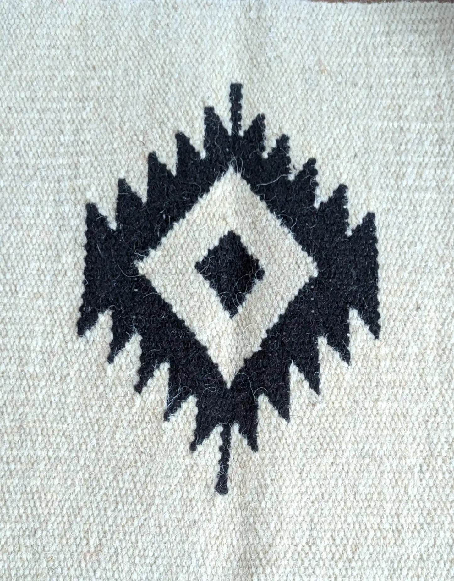 Motif kilim noir sur fond crème, détail du losange central tissé à la main