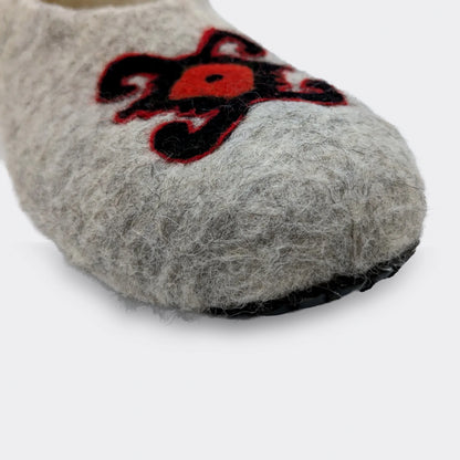 Détail du dessin de tortue sur chausson en feutre gris. Le motif ancien symbolise stabilité et mémoire dans l’art textile de Pirot. Vue en gros plan.