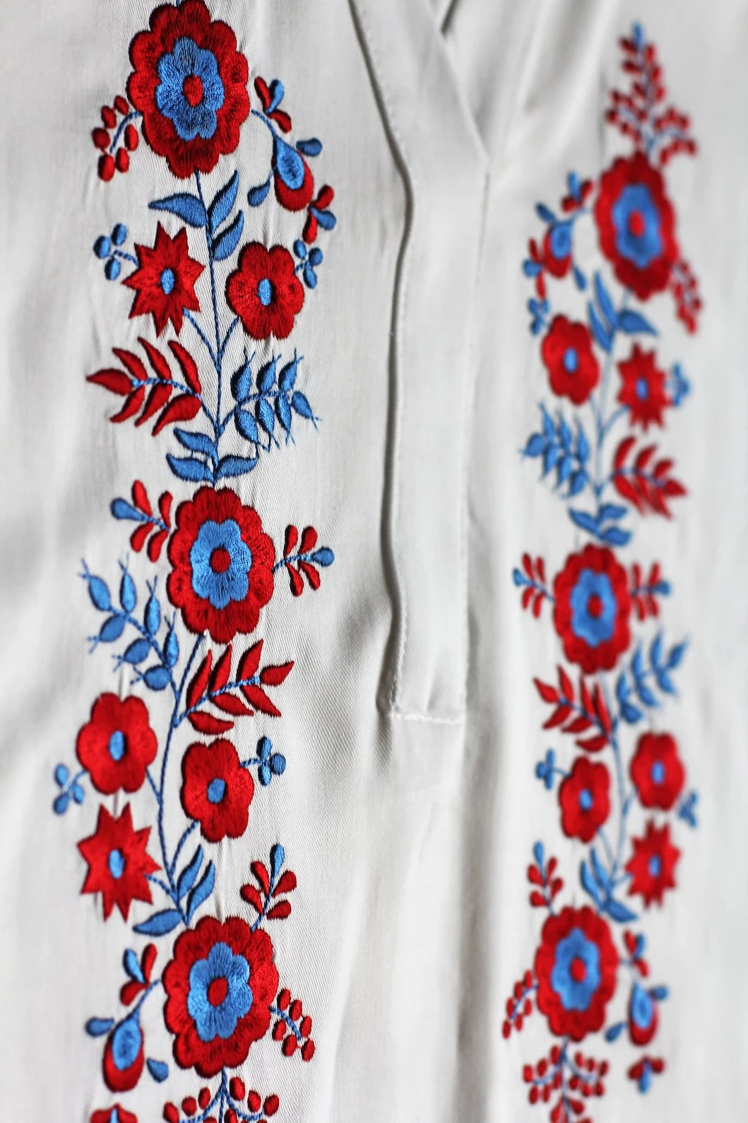 Détail de la broderie traditionnelle Palóc aux motifs floraux symétriques rouge et bleu.
