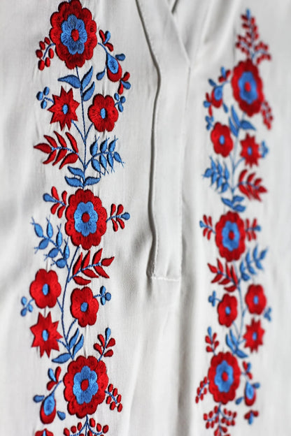 Détail de la broderie traditionnelle Palóc aux motifs floraux symétriques rouge et bleu.