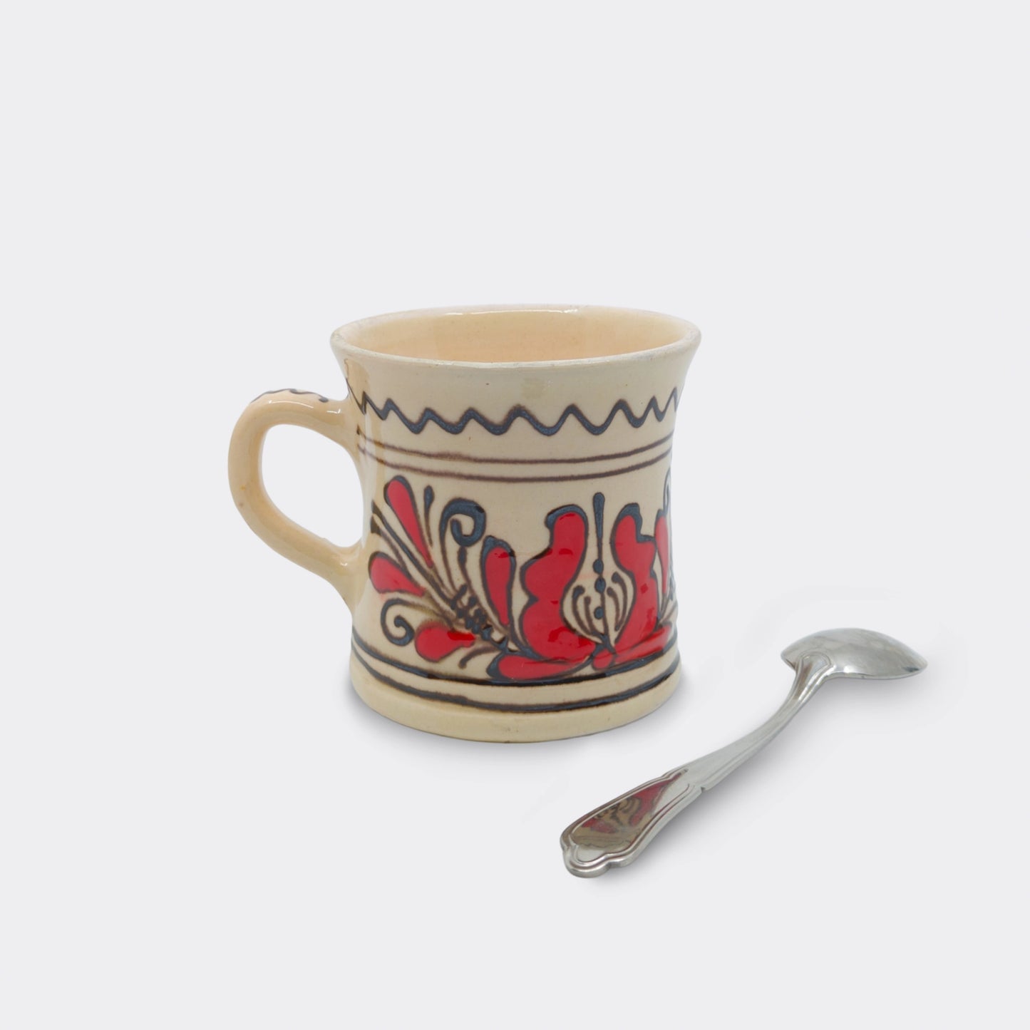 Tasse artisanale roumaine en céramique de Corund, lignes brun-noir et motif székely rouge. Forme cintrée.