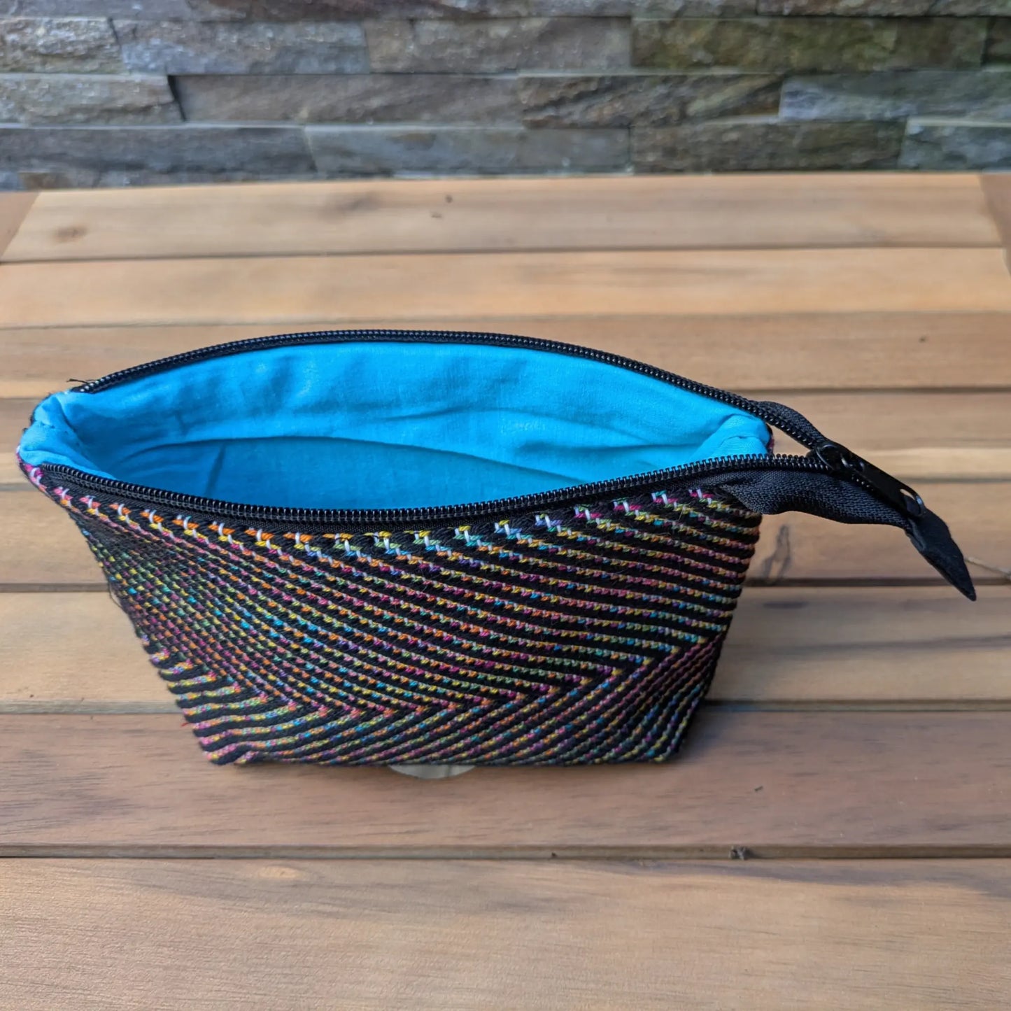 Nécessaire de toilette tissé main en chevrons, ouvert sur une doublure bleue avec fermeture zippée.