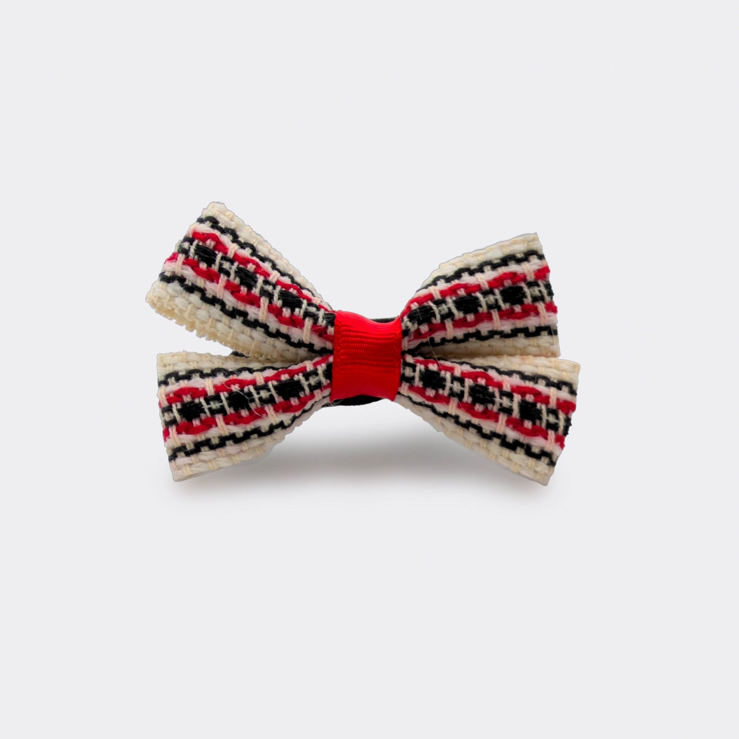 Nœud papillon avec motifs rouges et noirs sur fond écru. Fixé sur un élastique cheveux noir. Un accessoire pratique pour attacher les cheveux.