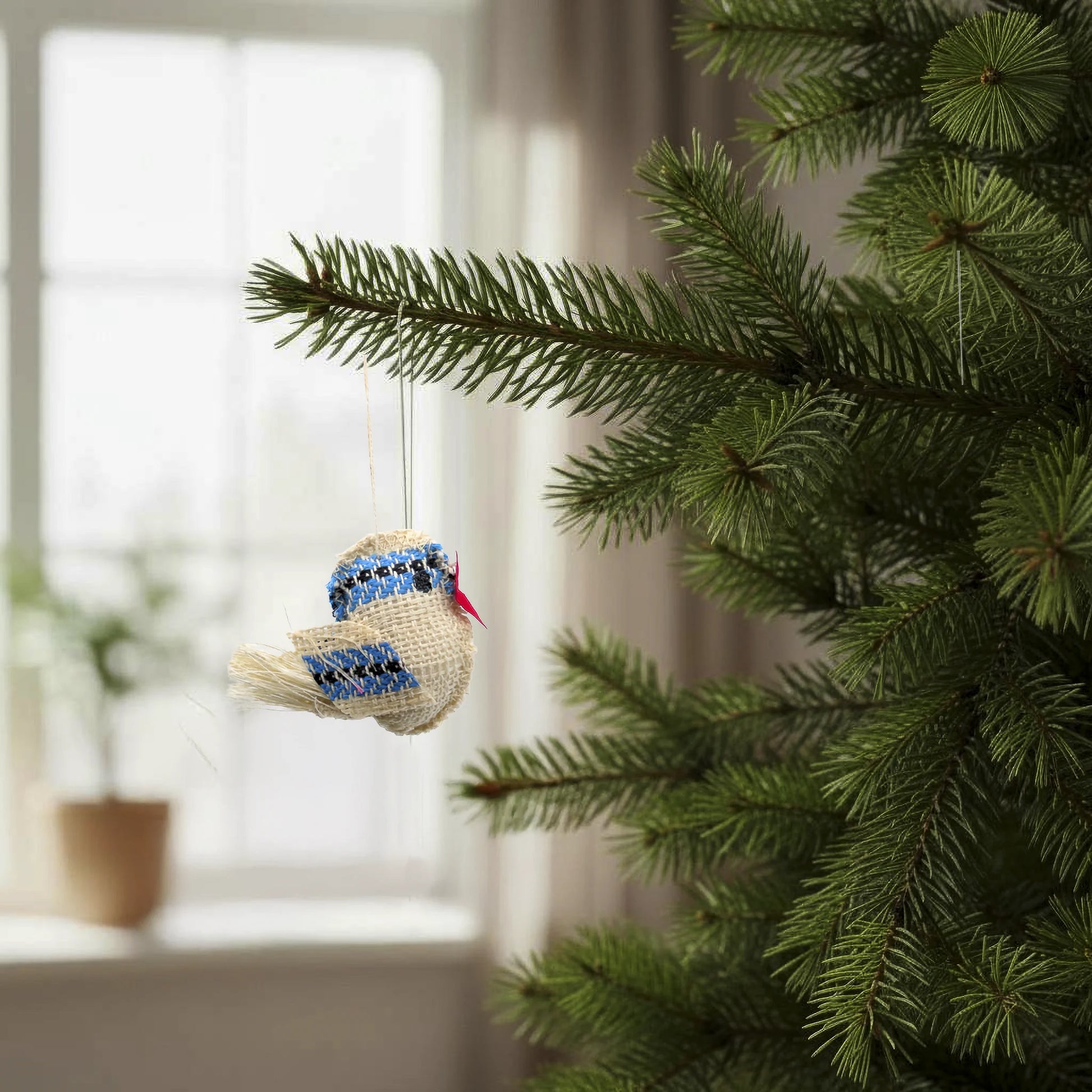 Petit oiseau bleu en coton, artisanal, suspendu dans un sapin. En provenance de la République Tchèque.