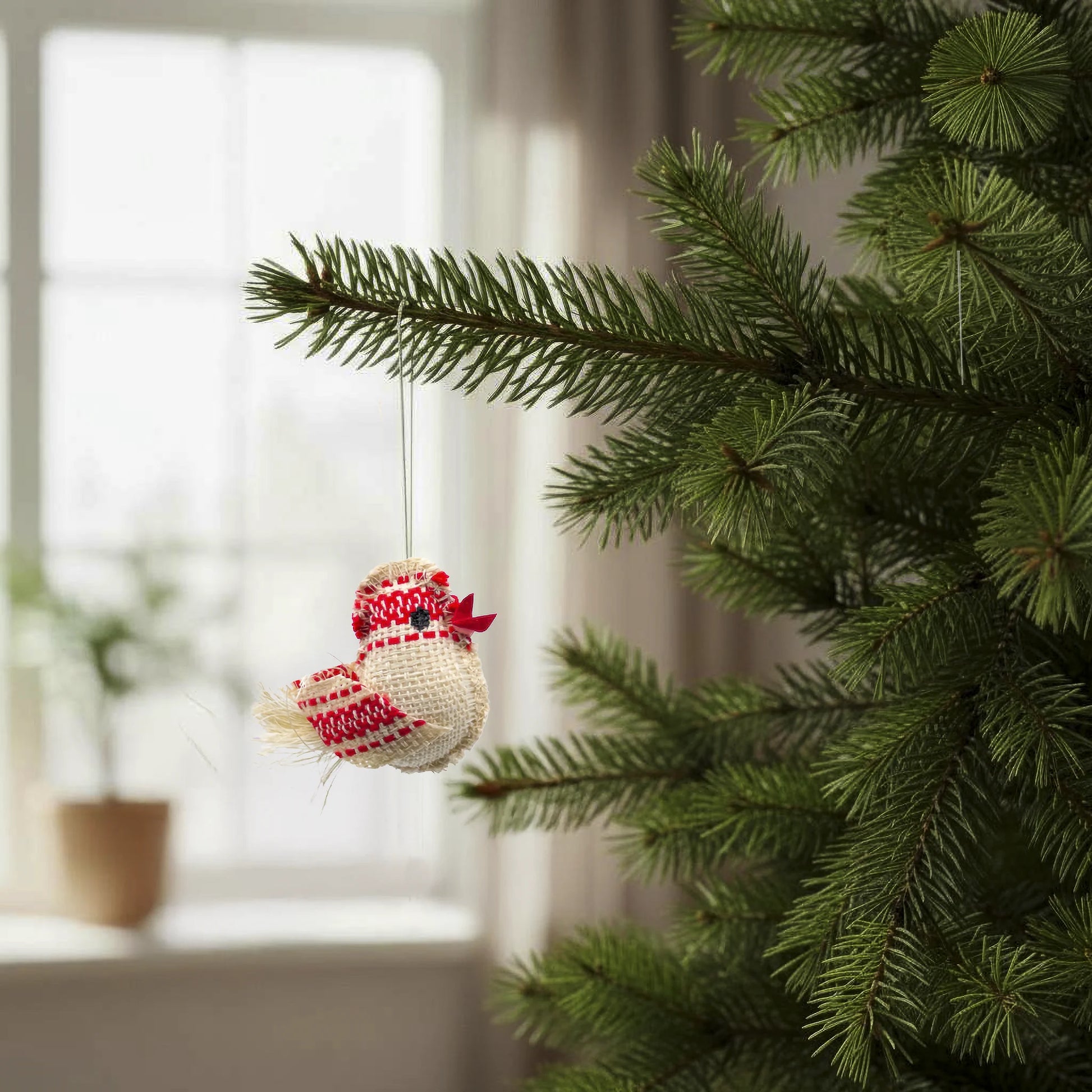 Petit oiseau rouge en textile, entièrement fait main en République Tchèque, suspendu dans un sapin