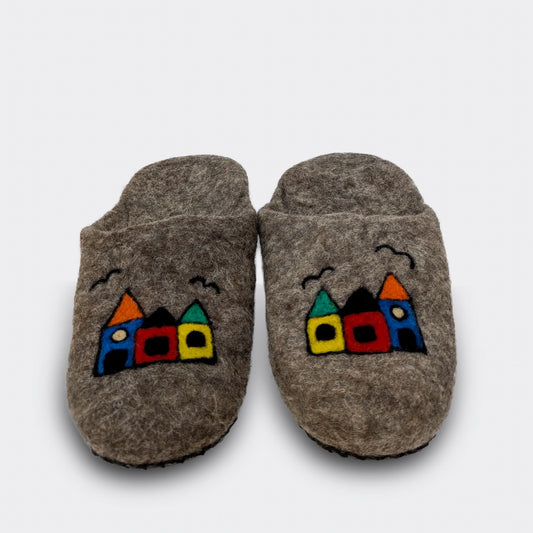 Pantoufles artisanales en laine grise ornées de petites maisons stylisées et joyeusement colorées, vue de face.