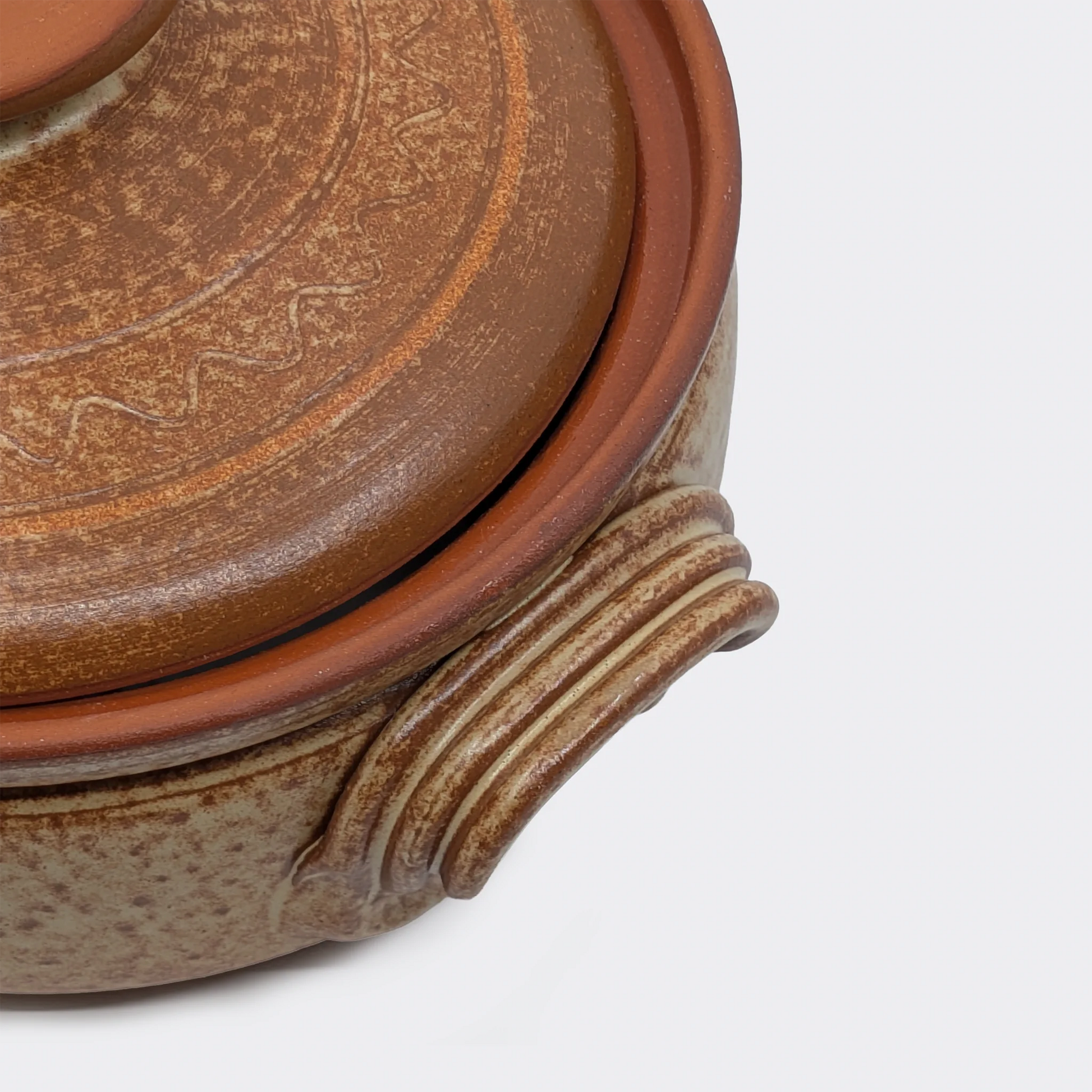 Gros plan sur la poignée latérale d’une petite cocotte en terre cuite 2 litres fabriquée à Corund.