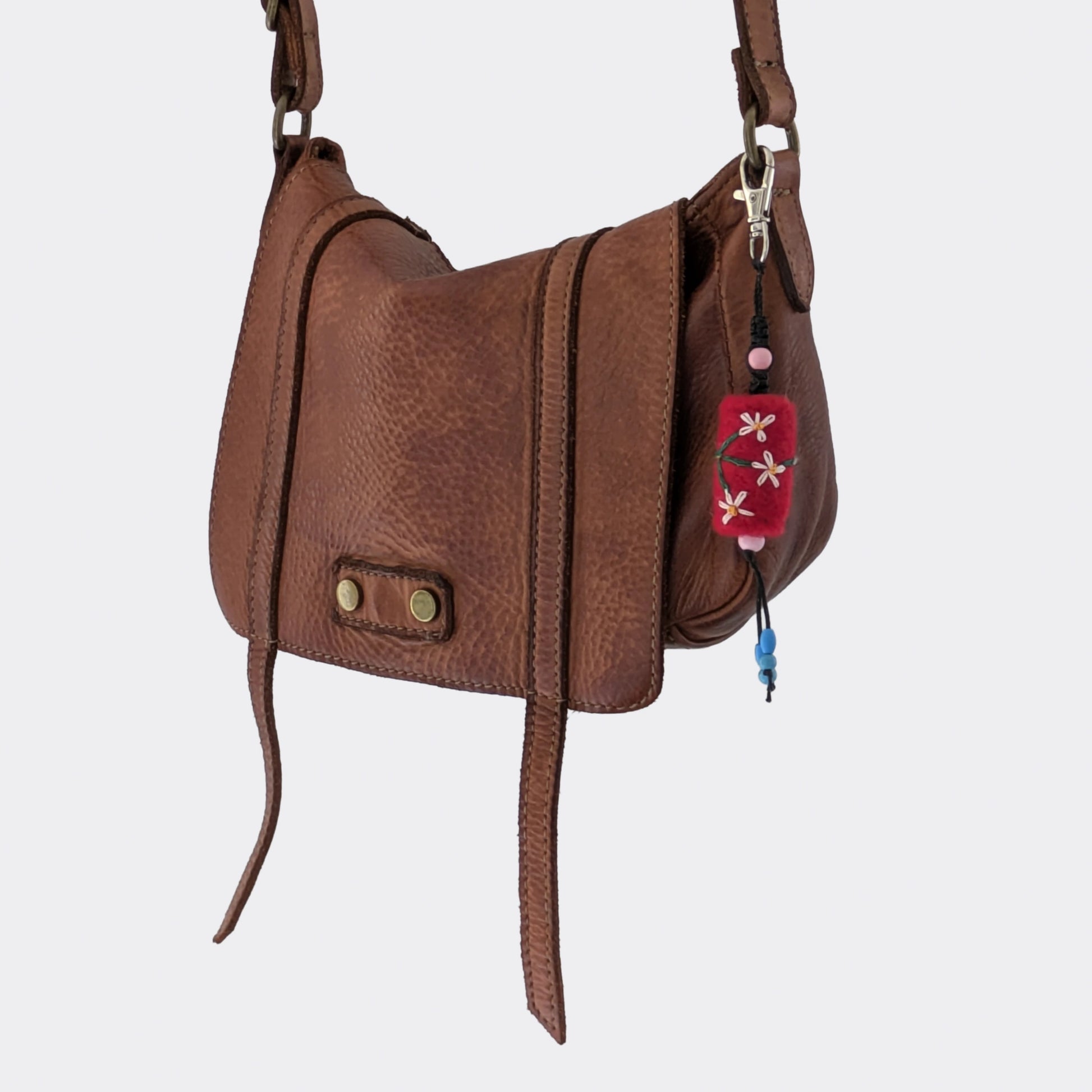 Porte-clé décoratif en feutrage manuel rouge accroché à un sac en cuir