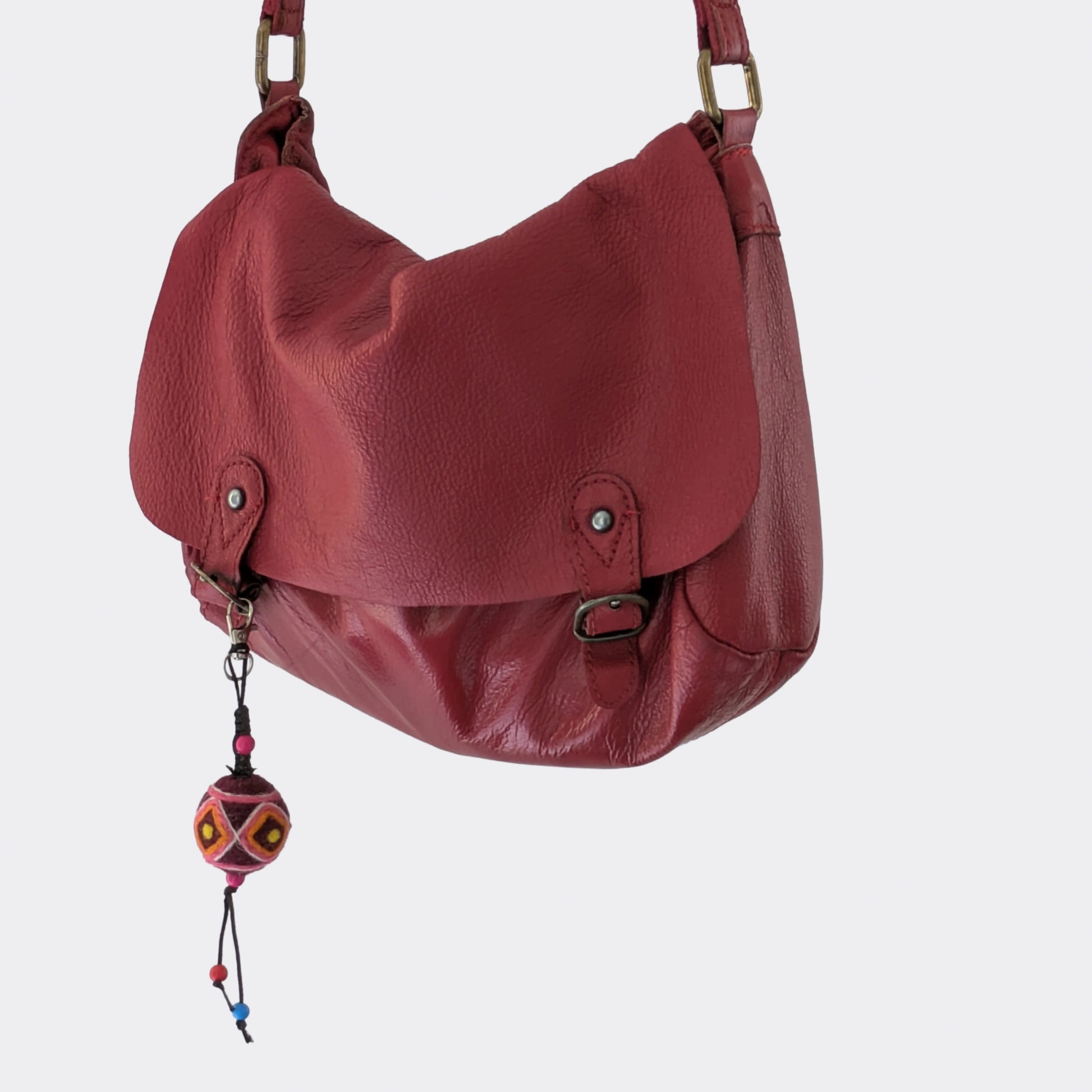 Porte-clé en laine feutrée rouge foncé réalisé à la main et accroché sur sac rouge