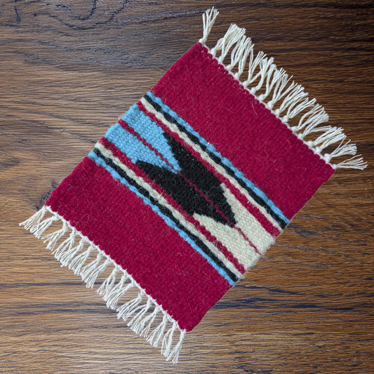 Sous-verre décoratif rouge tissé au Monténégro sur une table en bois