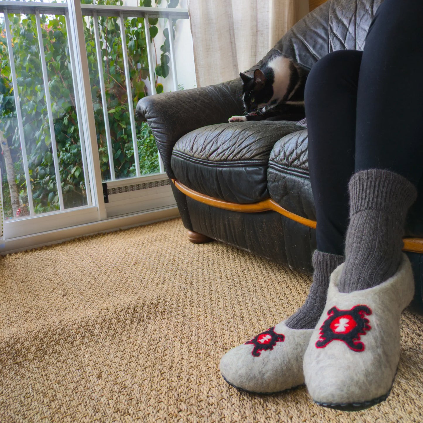 Des chaussons en feutre portées une femme laissent apparaitre un symbole issu des Balkans : une tortue stylisée fréquemment tissée sur les Kilims