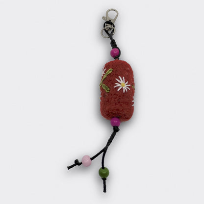 Breloque Tania de forme cylindrique en feutre rouge avec motifs floraux, petit mousqueton et perles colorées